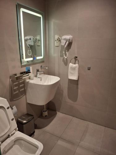 a bathroom with a sink and a toilet and a mirror at فندق الفال الشمالي الفندقية in Ḑubā