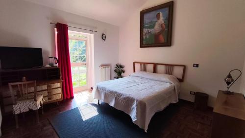 a bedroom with a bed and a television and a window at La Caldara House in Manziana