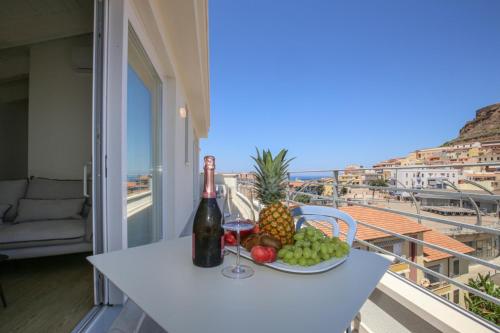 a table with a plate of fruit and a bottle of wine at Suite HollidayHouse - vista mare in Castelsardo
