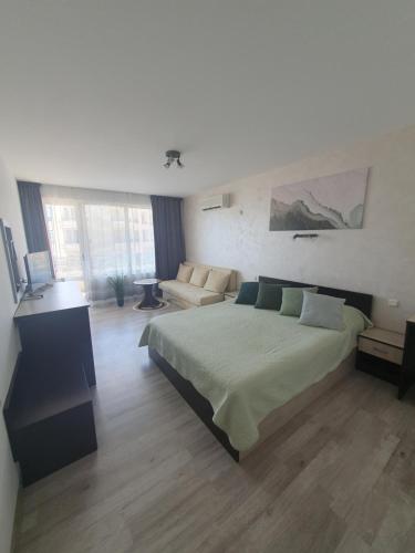 a bedroom with a large bed and a couch at студия ЛИЛИЯ in Tsarevo
