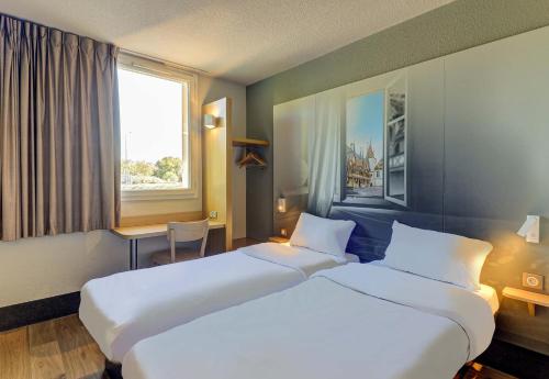 a hotel room with two beds and a window at B&B HOTEL BEAUNE Nord in Savigny-lès-Beaune