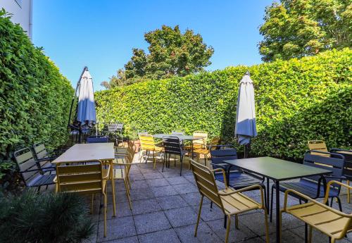 a patio with tables and chairs and umbrellas at B&B HOTEL BEAUNE Nord in Savigny-lès-Beaune