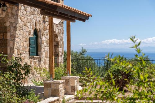 a stone building with a green door and the ocean at Joanna's Stone Villas in Vasilikos
