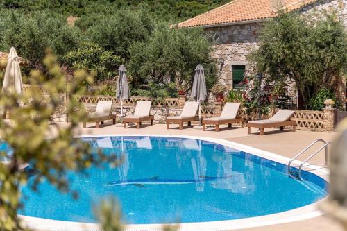 a swimming pool with chairs and umbrellas in a resort at Joanna's Stone Villas in Vasilikos