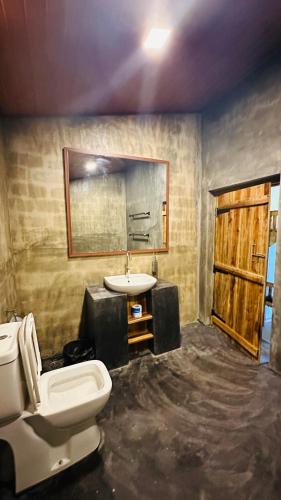 a bathroom with a white toilet and a sink at Hangten's Surf Skate Hostel in Arugam Bay