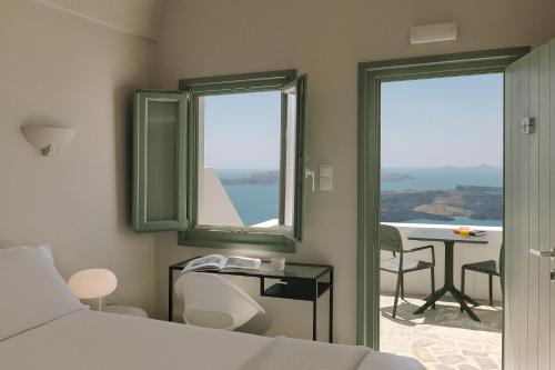 a bedroom with a bed and a table and a window at Agave Santorini Design Boutique Hotel in Imerovigli