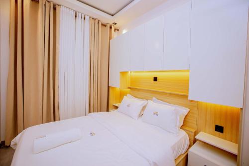 a white bed with white pillows in a bedroom at The Moon Apartment in Kigali