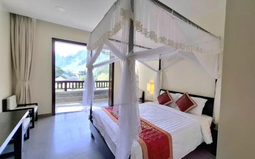 a bedroom with a canopy bed with a large window at Sài Gòn - Bản Giốc Resort in Lũng Niêo