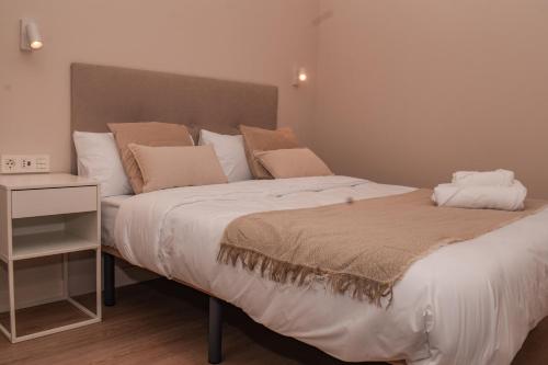 una camera da letto con un grande letto con lenzuola e cuscini bianchi di NIDOM experience a Madrid