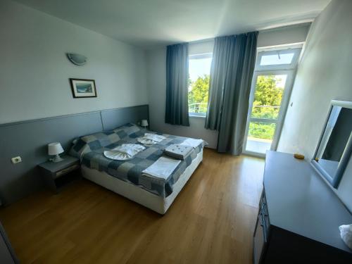a bedroom with a bed and a large window at Nushev Hotel in Sveti Vlas