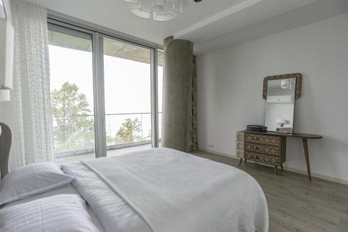 a bedroom with a bed and a large window at Green Cape Botanico in Batumi