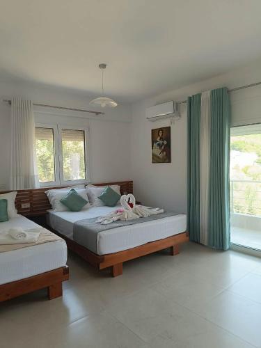 a bedroom with two beds and two windows at Athina Rooms in Himare