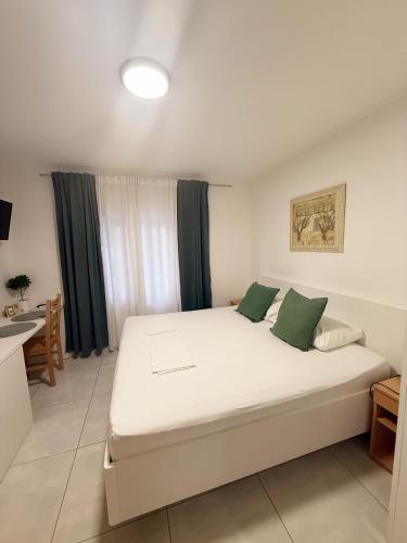 a bedroom with a large white bed with green pillows at Sobe Šušanj in Karlobag