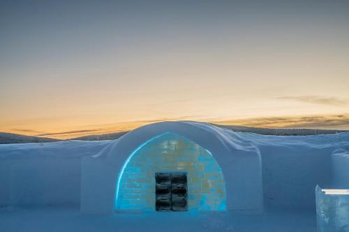 an igloo in the snow with a sunset in the background at IceHotel in Jukkasjärvi