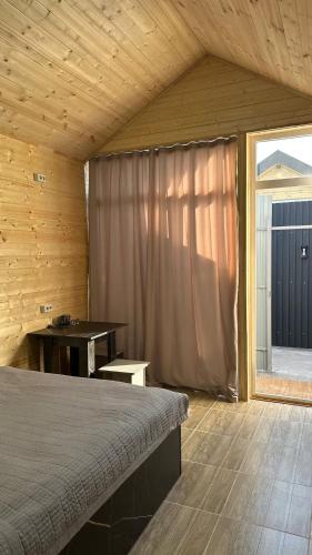 a bedroom with a bed and a table and a window at Абая 29 гостевые домики in Kosh-Tegirmen
