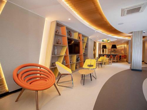 a room with chairs and tables and a book shelf at ibis Styles Lima Benavides Miraflores in Lima