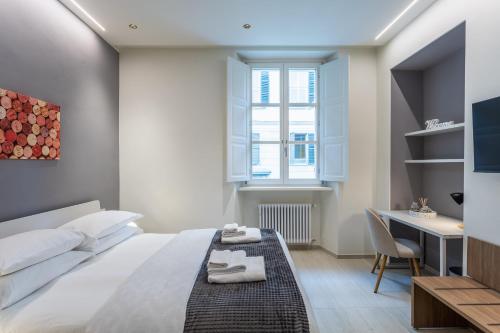 a bedroom with a bed and a desk and a window at Civico Due in Cuneo