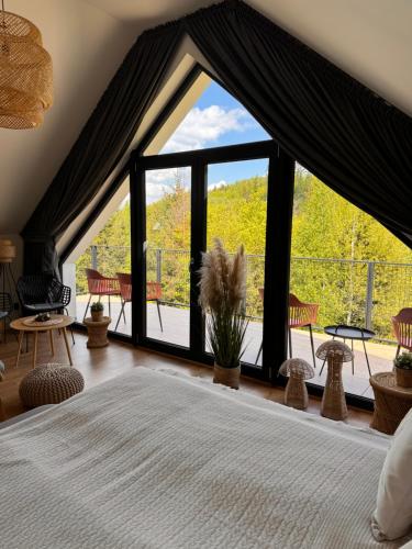 a bedroom with a bed and a large window at Domki Dwa jelonki - balia z jacuzzi i sauna in Wisła