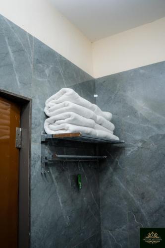 a pile of white towels on a shelf in a bathroom at Sweekar Executive in Tuljapur