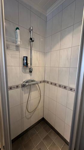 a shower with a hose in a tiled bathroom at Charming Casa Hauge BB Sunset Room in Sandane