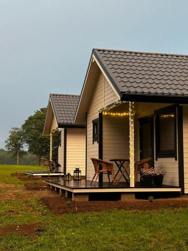 a small house with a porch and a patio at Przystanek Krag - kazdy domek ma prywatna balie! Do tego wlasna prywatna plaza, pomost, lodka, kajaki, strefa ciszy, darmowy parking, grille , miejsce na ognisko in Krąg