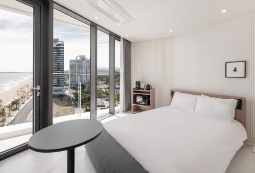 a bedroom with a white bed and a large window at Plott The Gak Yangyang in Yangyang