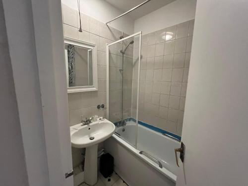 a white bathroom with a sink and a bath tub at Cozy Spacious Flat in South Norwood