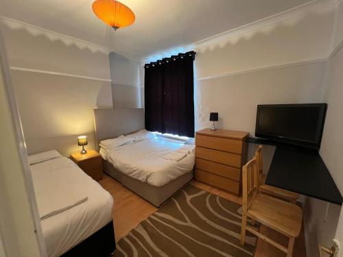 a small room with two beds and a television at Cozy Spacious Flat in South Norwood