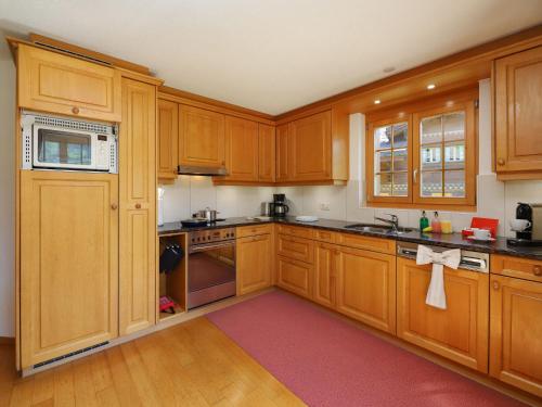 a kitchen with wooden cabinets and a red rug at Apartment Chalet Nagano by Interhome in Grindelwald