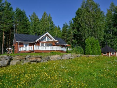 a house on a hill with a field and trees at Holiday Home Kannelpirtti 2 by Interhome in Puromäki