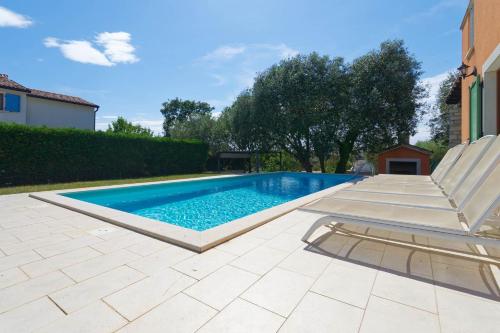 a swimming pool with a bench and a chair at Villa Ana by Rent Istria in Vilanija