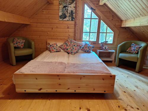 a large bed in a wooden room with two chairs at Szumi szumi LAS in Joniec