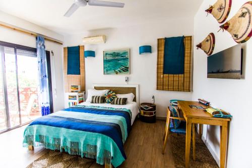 a bedroom with a bed and a wooden desk at Maison Sahel - African Art & Coastal Serenity in Dakar
