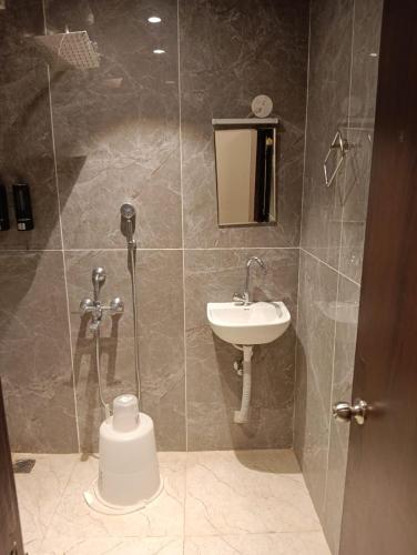 a bathroom with a shower with a sink and a toilet at VMR Hotel Port Blair in Jangli Ghāt