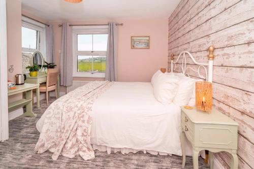 a bedroom with a white bed and a desk at Britmead Guesthouse in West Bay