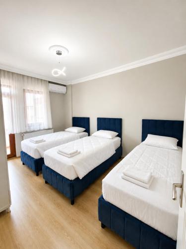 three beds in a room with white walls and wooden floors at Blue61 Residence Airport in Pelitli