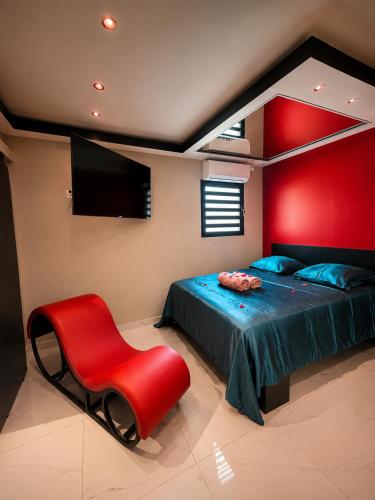 a red bedroom with a bed and a red chair at Love room Coconut Secret in Le Gosier
