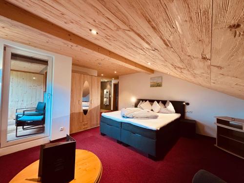 a bedroom with a bed and a table in a room at Pension Bergheim in Tannheim