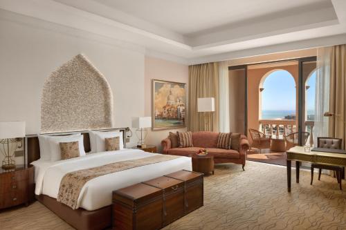 a bedroom with a large bed and a living room at Marsa Malaz Kempinski, The Pearl in Doha