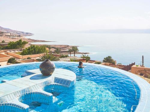 a swimming pool with a view of the ocean at Mövenpick Resort & Spa Dead Sea in Sowayma