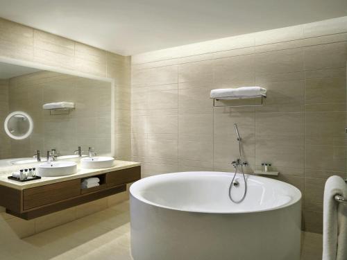 a large bathroom with a tub and two sinks at Movenpick Hotel & Convention Centre KLIA in Sepang