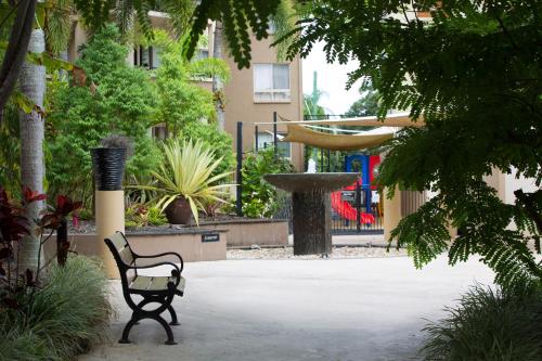 a park bench with a fountain in a courtyard at The Lakes Resort Cairns in Cairns