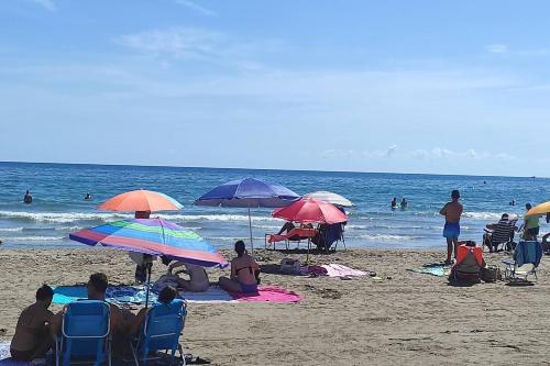 a group of people sitting on the beach under umbrellas at Promar La Pineda Port Aventura in La Pineda