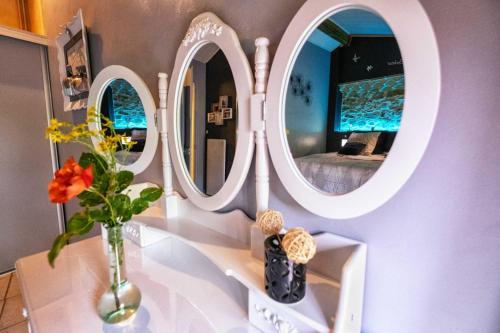 a room with three mirrors and a vase with flowers at Grésigne in Larroque