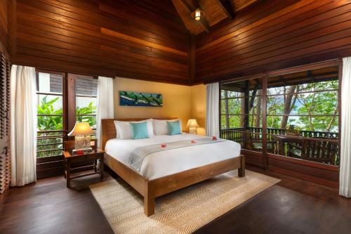 a bedroom with a bed in a room with windows at Enchanted Island Resort in Mahe