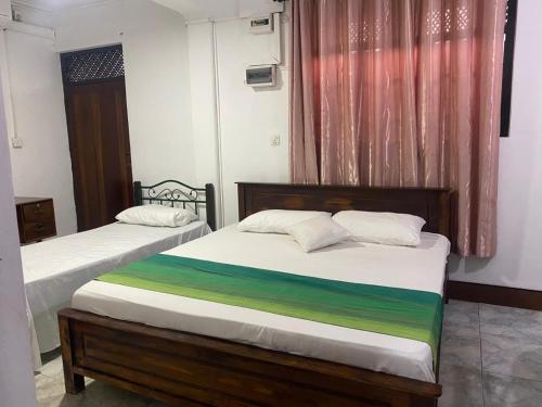 a bedroom with two beds and a window at Courtyard Hostel Negombo in Negombo