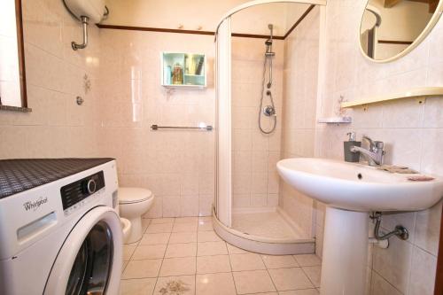 a bathroom with a washing machine and a sink at S'Archittu Sea Retreat in S'archittu Cuglieri