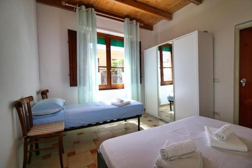 a bedroom with two beds and a chair and a window at S'Archittu Sea Retreat in S'archittu Cuglieri