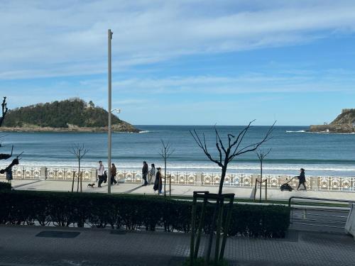 a group of people walking on a sidewalk near the beach at Samsara in San Sebastián