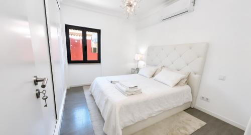 a white bedroom with a white bed and a window at Solstice Villa Private Pool & BBQ Cascais in Alcabideche